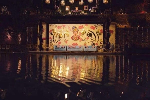 Wedding celebration: night view of illuminated stage with painted backdrop reflected in pool water