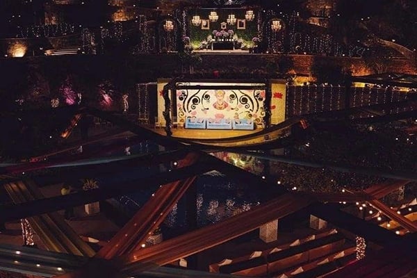 Wedding celebration: aerial night view of stage across pool with overhead draped fabric and lights