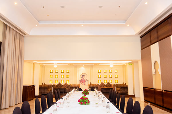 Zuma hall: long table with black chair covers and red flower centrepieces in a high-ceilinged room