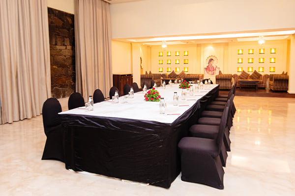 Zuma hall: long table with black chair covers, flowers and curtains in a marble-floored room