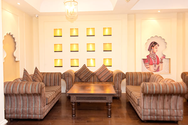 Zuma hall: striped sofas, wooden coffee table, lit wall niches and a painted portrait