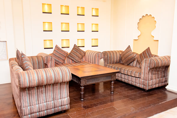 Zuma hall: striped sofas around wooden coffee table with lit wall niches and arch motif