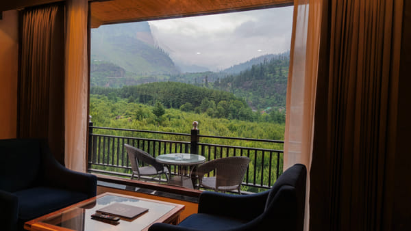 Private balcony of a Luxurious Room at Nazaara Luxe Retreat overlooking snow-dusted mountain ridges under daytime light