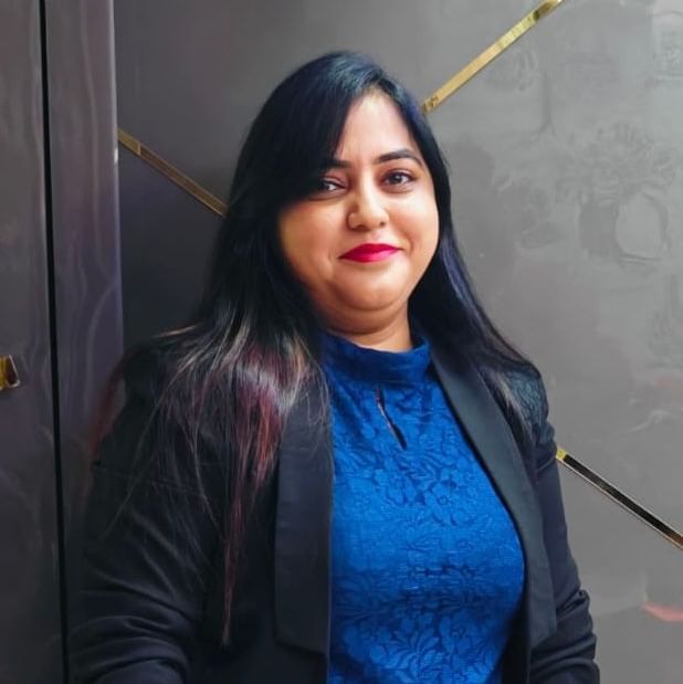 Portrait of Ashwini Takle with long hair, wearing a blue dress and black blazer.