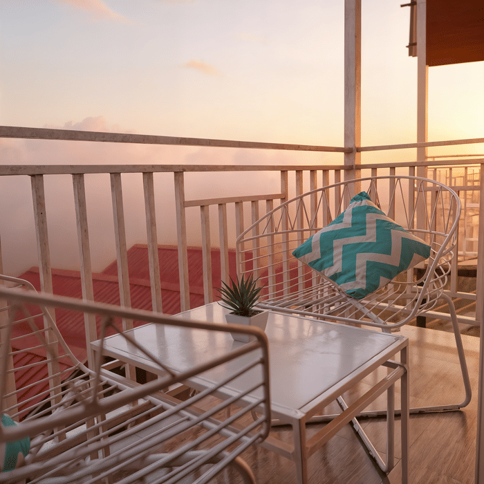 Teal balcony seating in the Premium Cottage at Nazaara Nature Retreat, overlooking Dalhousie's pine-covered hillside.