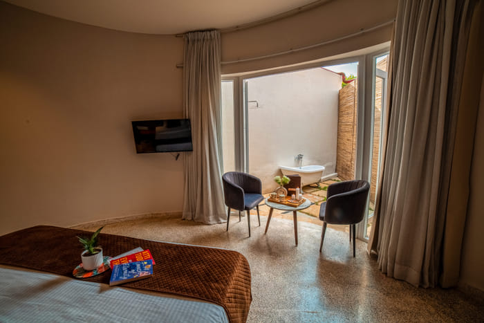 Luxurious Cabana Cottage bedroom opening onto a private patio at Nazaara Hills Retreat, Udaipur.
