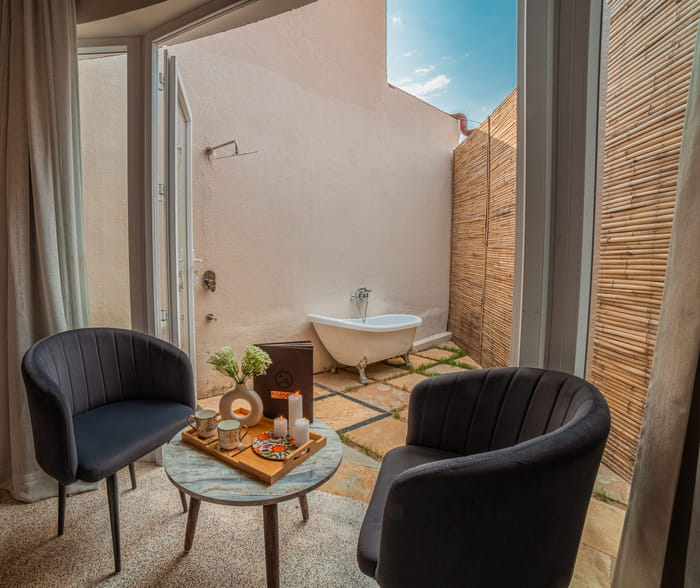 Patio seating beside the outdoor tub of the Luxurious Cabana Cottage at Nazaara Hills Retreat, Udaipur.