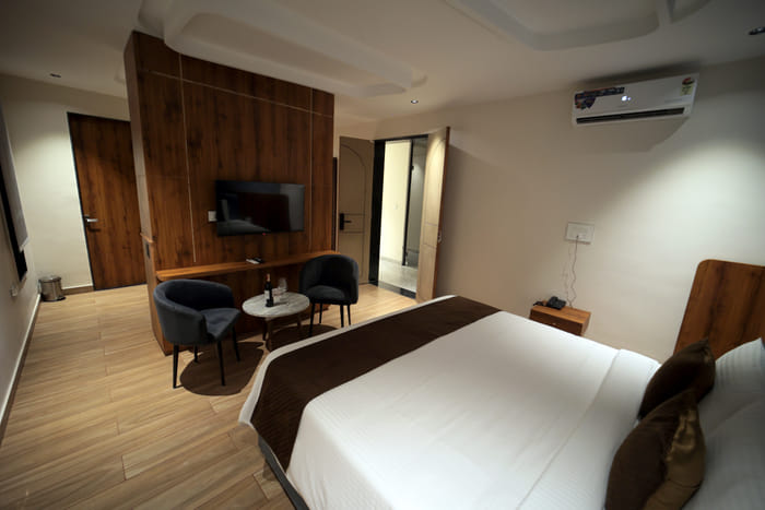 King bed facing the smart TV in the Premium Plunge Pool Room at Nazaara Hills Retreat, Udaipur.