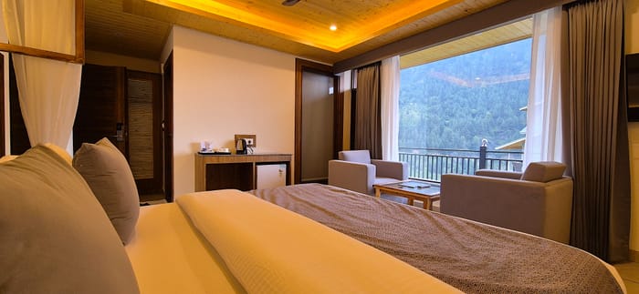 King bed beside a wooden console holding the tea and coffee maker in the Superior Room at Nazaara Luxe Retreat, Manali