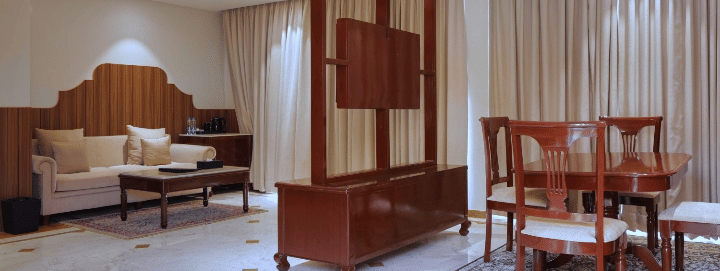 Royal Suite at Raj Leela Heritage Resort by Estherea, Ranakpur featuring a sofa, coffee table, partition divider, and dining table with 4 chairs.