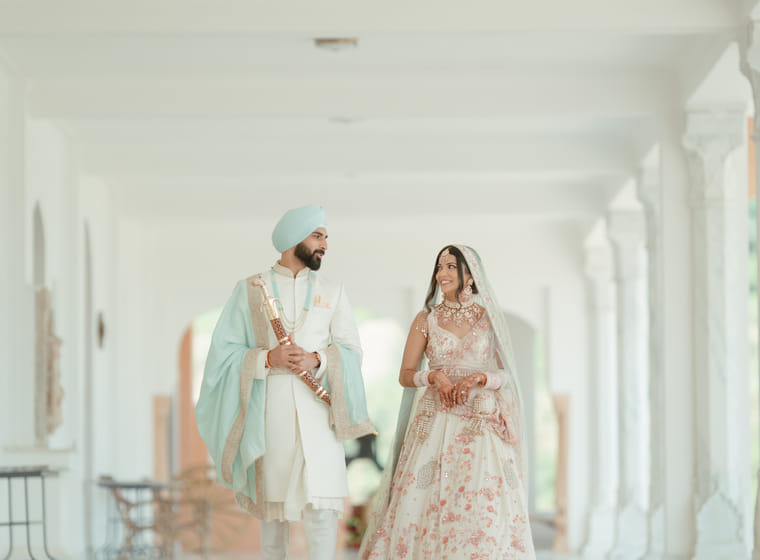 A couple walks together through a sunlit white colonnaded corridor