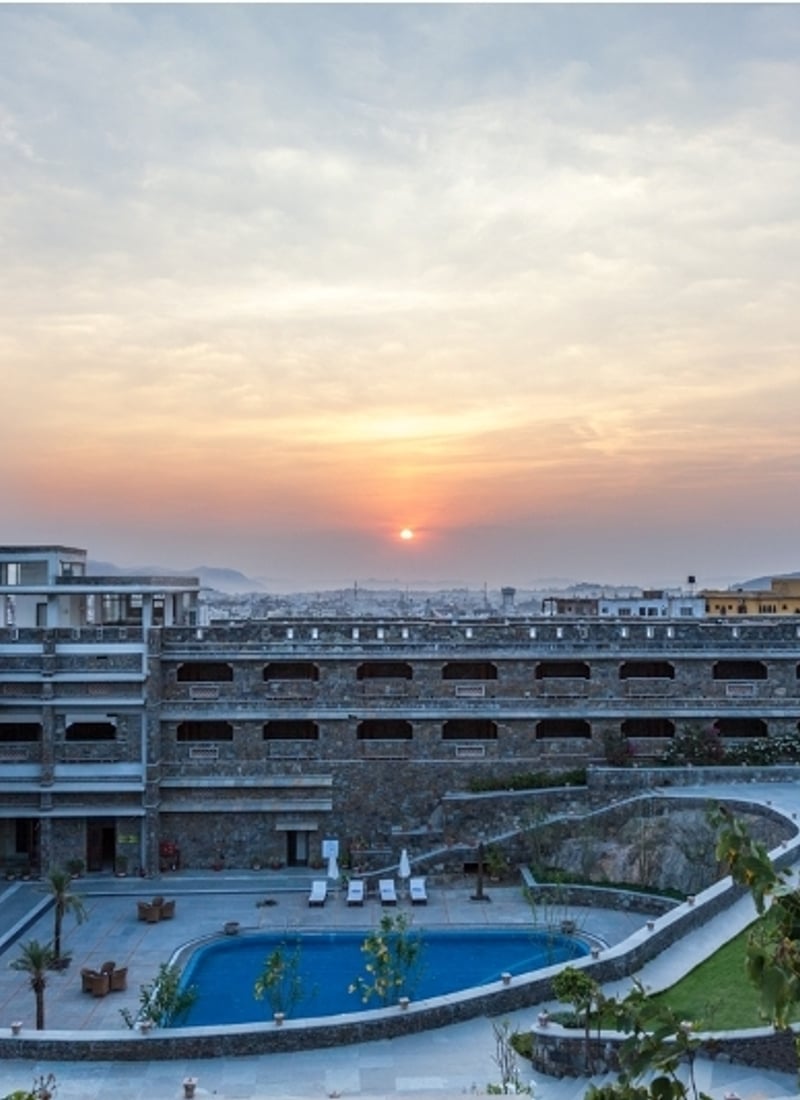 Sunrise over the stone buildings and courtyard pool of Ramada by Wyndham Udaipur Resort and Spa