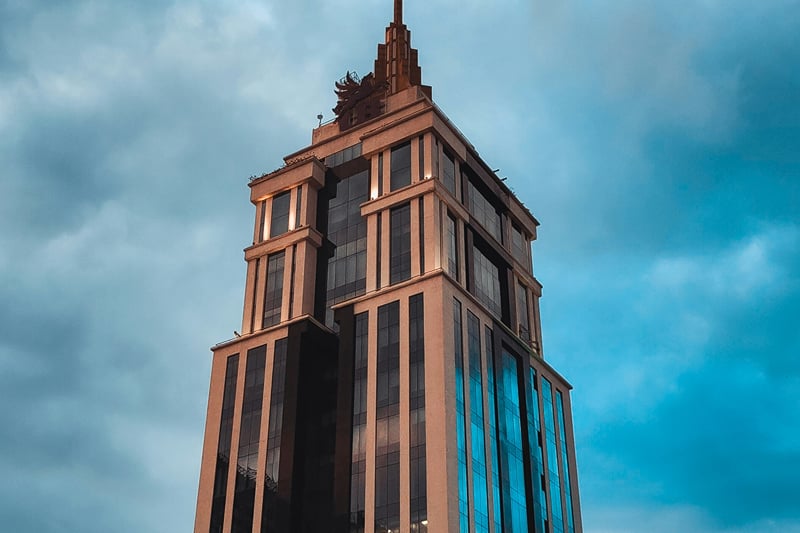 The UB City tower rising against a cloudy blue sky
