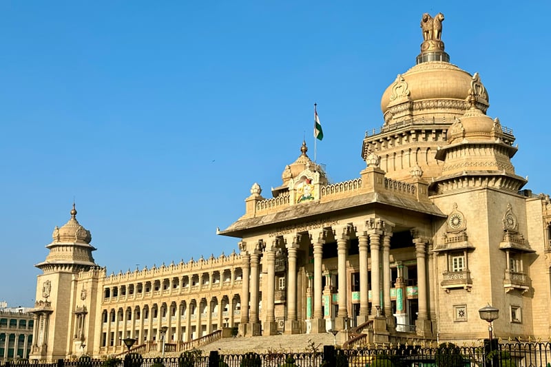 The granite facade and central dome of Vidhana Soudha against a blue sky