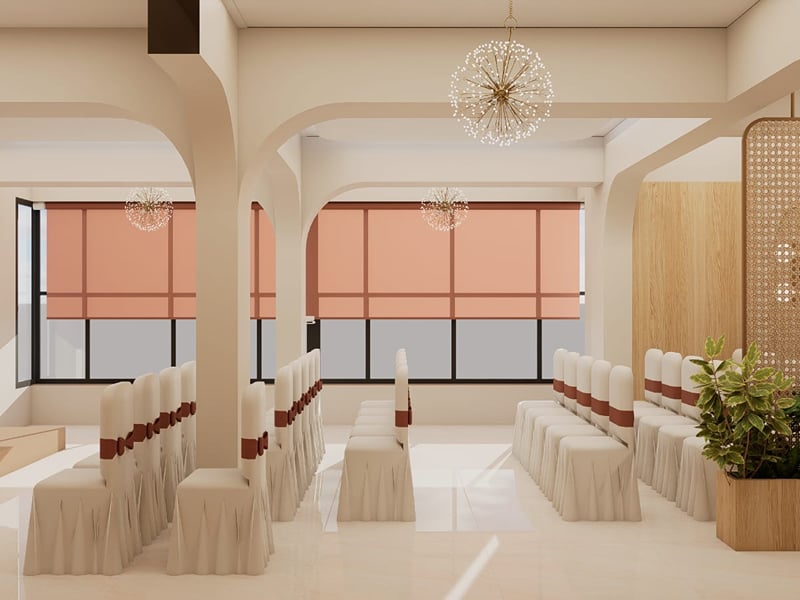 Coral banquet hall with draped chairs set in rows between arched pillars | Shirgaonkar Beach Resort