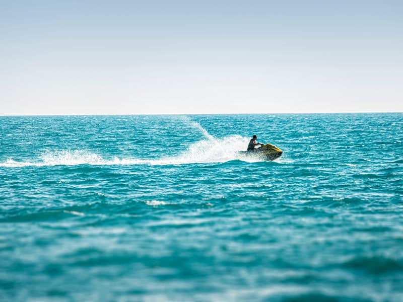 Jet ski cutting a white wake across open turquoise water | Shirgaonkar Beach Resort