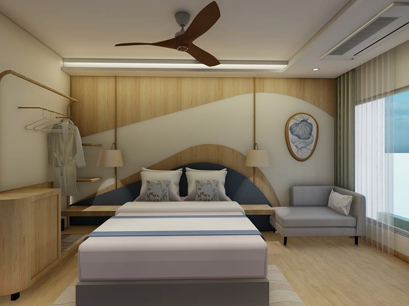 King bed beneath an arched navy headboard, with a grey sofa beside the window | Shirgaonkar Beach Resort