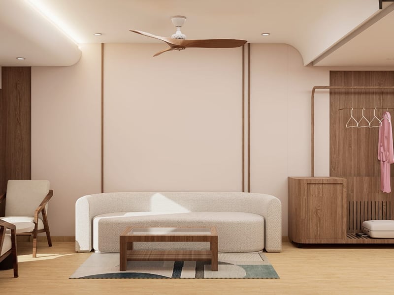 Cream sofa and low table in the Suite living area, with a wooden cabinet alongside | Shirgaonkar Beach Resort