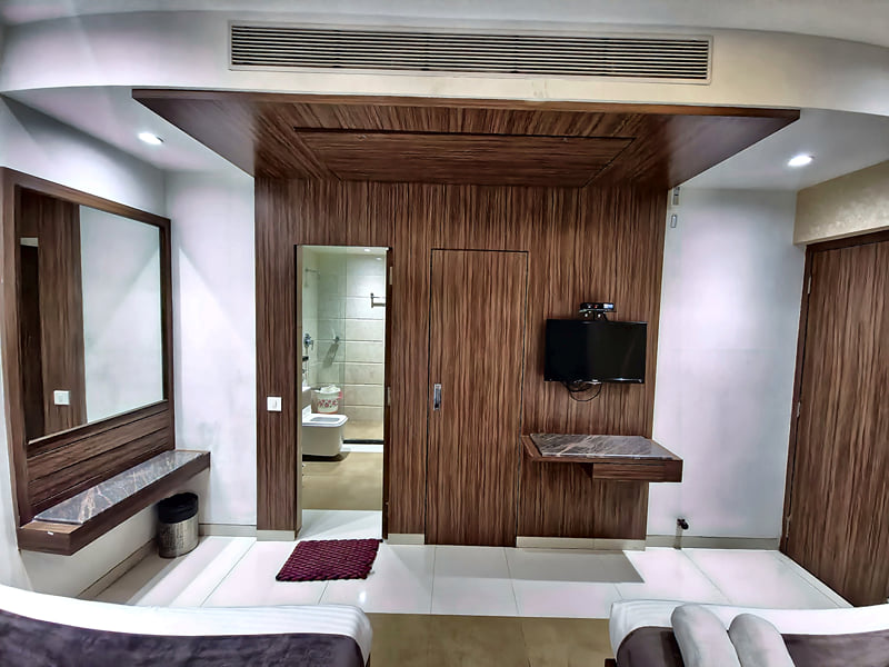 Wardrobe, vanity mirror and wall-mounted TV in a guest room