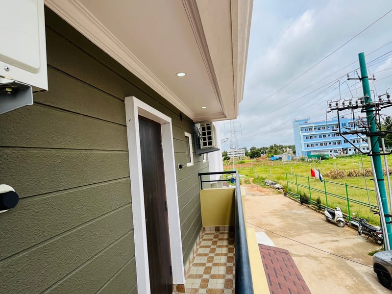 Private balcony of the Standard Balcony Room at Value Inn, Bangalore Airport with chequered flooring and views over open green fields
