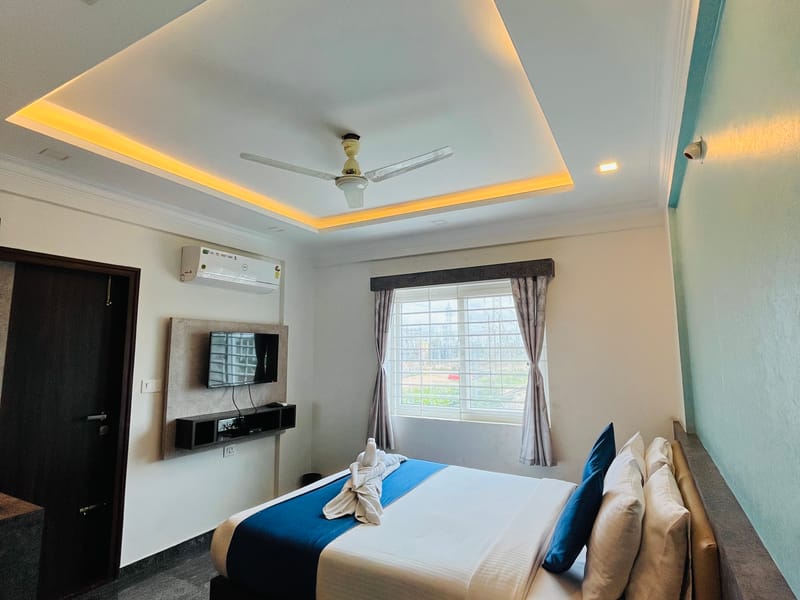 Standard Balcony Room at Value Inn, Bangalore Airport with a queen bed, an air conditioner, and a bright window towards the balcony side