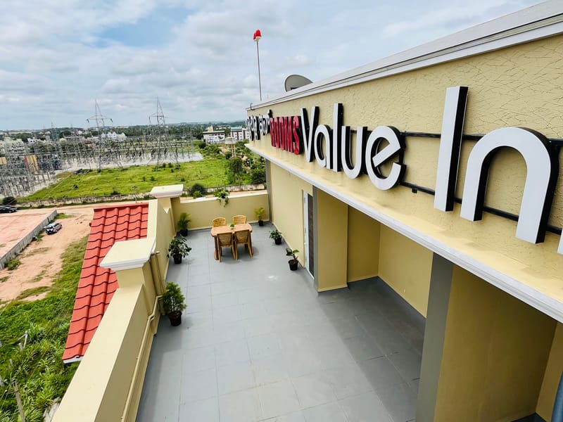 Rooftop terrace at Value Inn, Bangalore Airport with the hotel name board and open green views across the Yelahanka countryside nearby