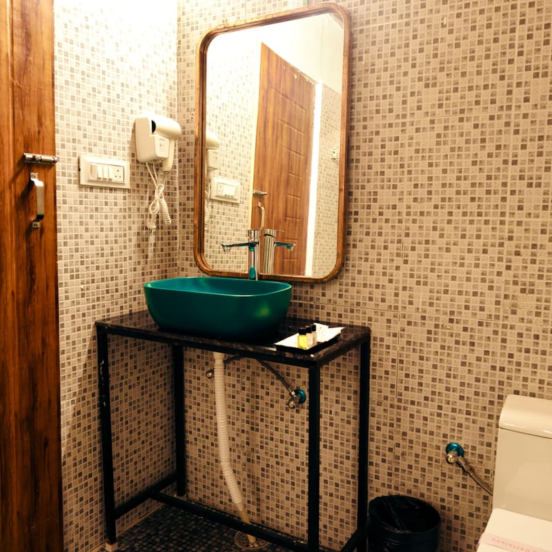 Cottage bathroom at Nazaara Nature Retreat with a teal vessel basin set atop a rustic wood-framed vanity mirror