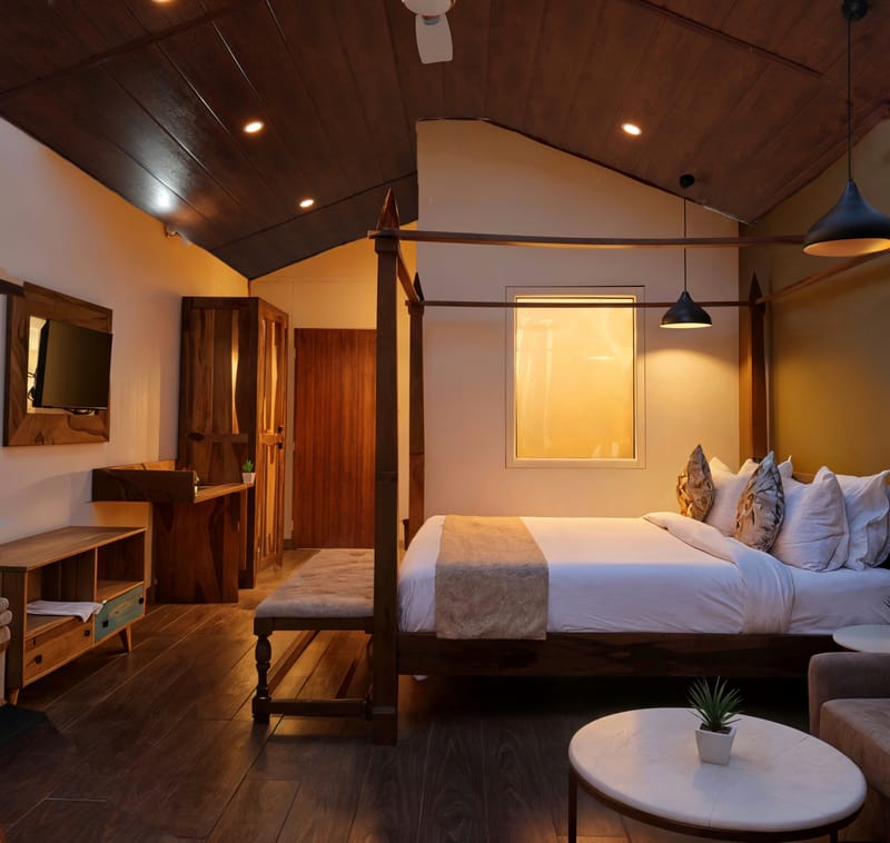 Luxurious Cottage bedroom at Nazaara Nature Retreat with warm timber detailing, a dressed bed, and forest-facing windows