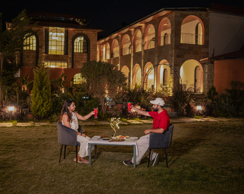 A couple toasting over dinner at Nazaara Hills Retreat, Udaipur.