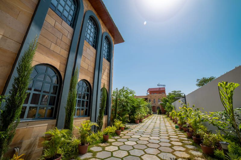 A hexagonal-paved walkway winding through Nazaara Hills Retreat, Udaipur, pictured in daylight.