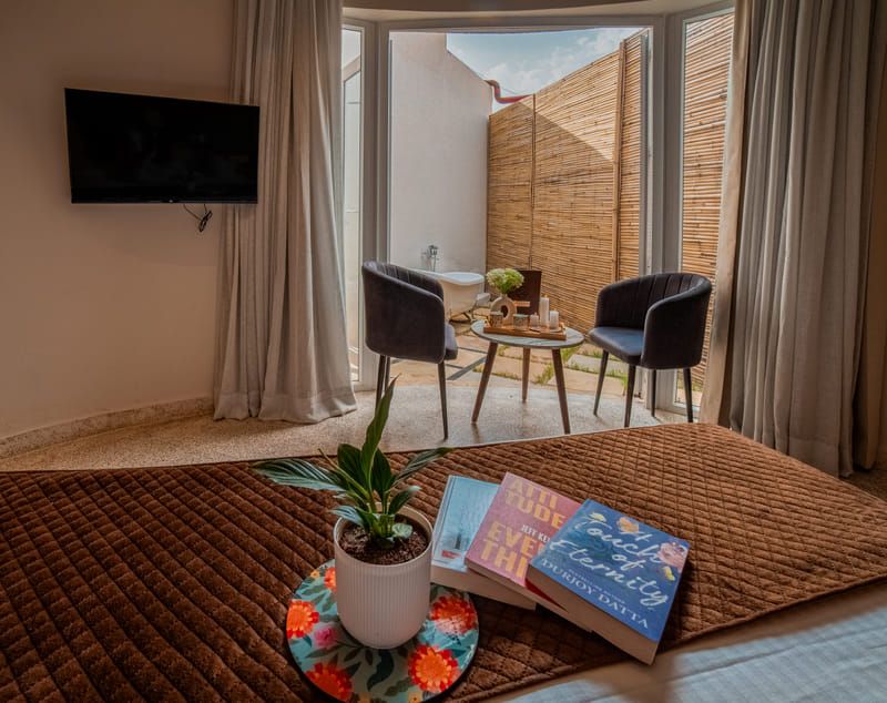 The Luxurious Cabana Cottage bed with a view of the private patio seating at Nazaara Hills Retreat, Udaipur.