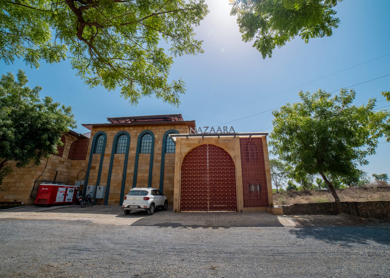 Nazaara Hills Retreat's main gate and entrance driveway, Udaipur, pictured in daylight.