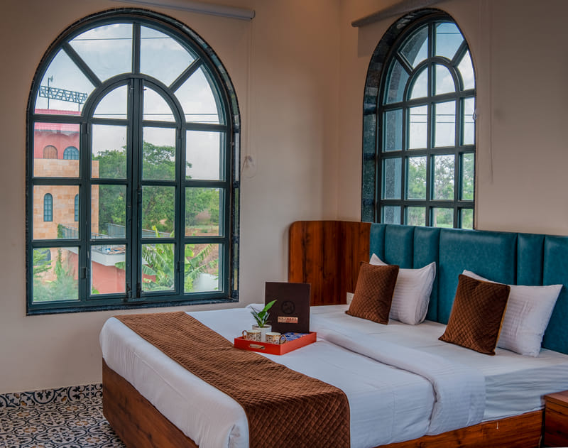Close-up of the bed in the Nazaara Family Suite at Nazaara Hills Retreat, Udaipur, beside arched windows.