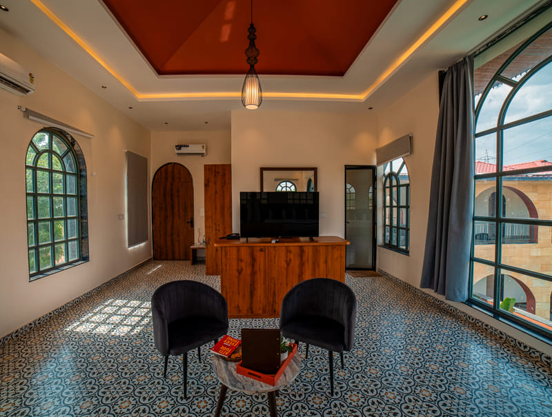 A television and lounge seating area in the Nazaara Family Suite at Nazaara Hills Retreat, Udaipur.