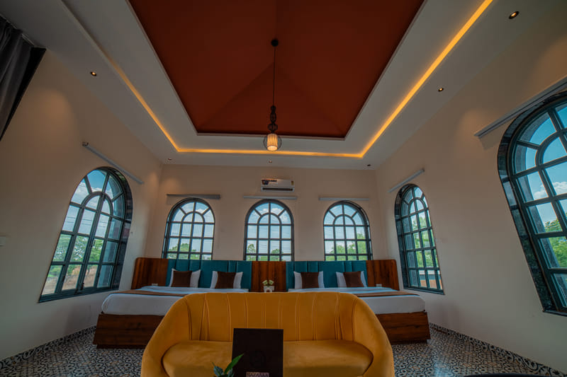 Twin beds in the Nazaara Family Suite at Nazaara Hills Retreat, Udaipur, beneath a pendant ceiling light.