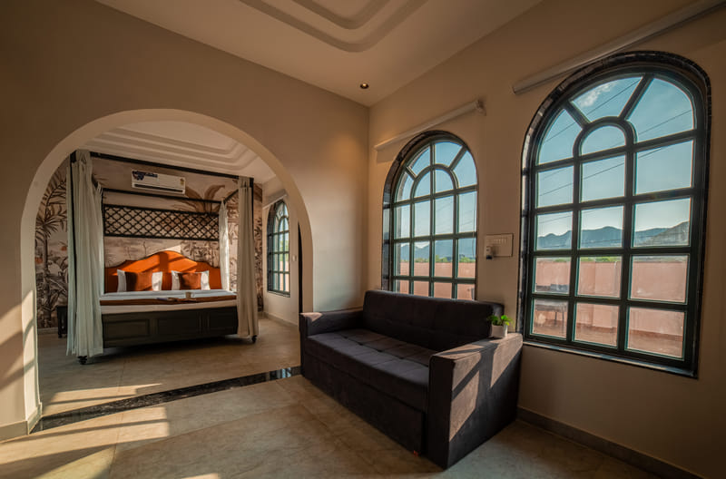 Sofa seating in the living area of the Nazaara Royal Suite at Nazaara Hills Retreat, Udaipur, beside arched windows.