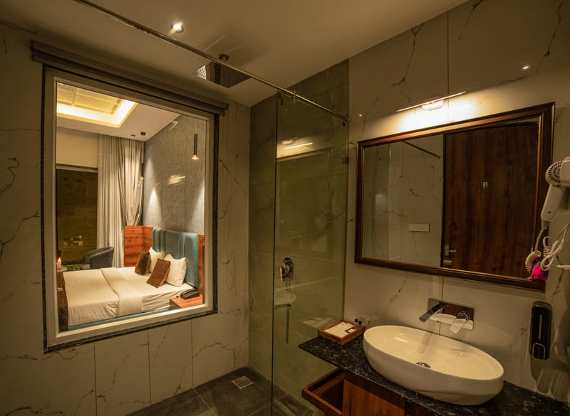 Premium Plunge Pool Room bathroom at Nazaara Hills Retreat, Udaipur, with a shower and window view.