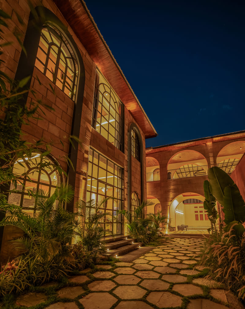 A lit walkway near the reception of Nazaara Hills Retreat, Udaipur, pictured at night.