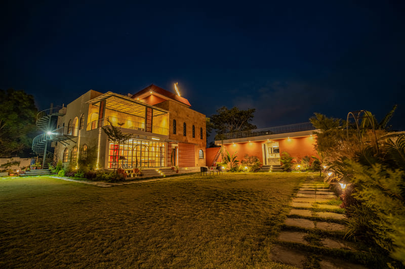 The restaurant building and lawn at Nazaara Hills Retreat, Udaipur, lit up at night.