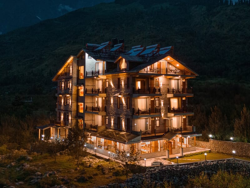 Aerial drone view of Nazaara Luxe Retreat's lit windows against the night sky, Manali