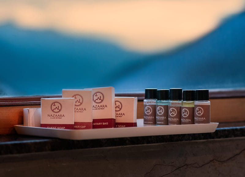 A tray of toiletries set by a window with a mountain view at Nazaara Luxe Retreat