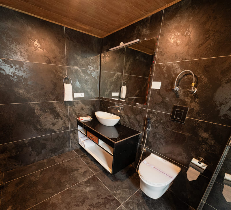 A dark-tiled bathroom vanity in one of the standard rooms at Nazaara Luxe Retreat