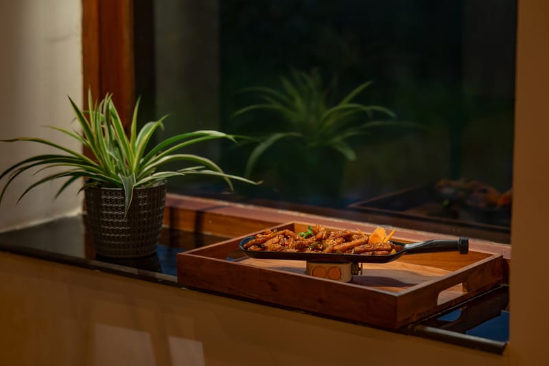 A tray of chicken served beside a potted plant at Restro & Café, Nazaara Luxe Retreat