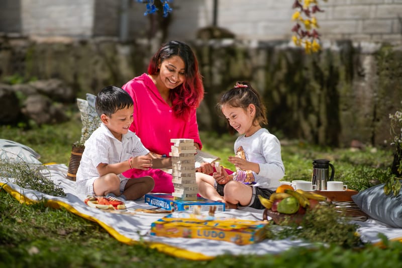 A family playing Jenga on the lawn at Nazaara Luxe Retreat