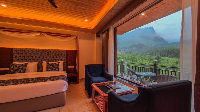 Luxurious Room bed at Nazaara Luxe Retreat positioned beside a window with a dramatic cliffside mountain view, special offer