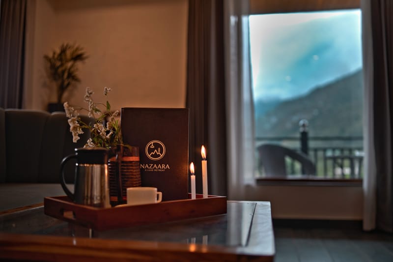A menu set beside coffee cups and candles at Restro & Café, Nazaara Luxe Retreat