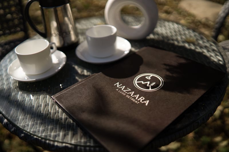 Coffee cups set on the table beside the menu at Restro & Café, Nazaara Luxe Retreat