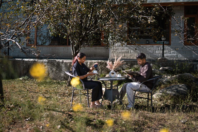 Guests seated at an outdoor table at Restro & Café, wooden furniture set against a mountain backdrop