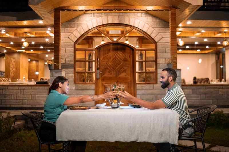 Glasses raised at an outdoor table at Restro & Café, Nazaara Luxe Retreat