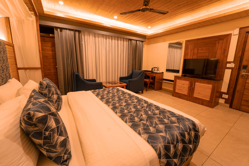 A canopy-draped bed at Nazaara Luxe Retreat, warm wooden furnishings lit by soft daylight